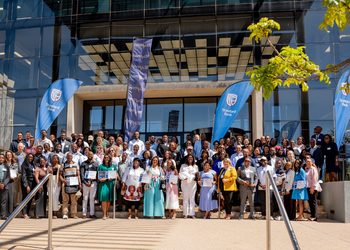 WhatsApp Image 2026-10-29 at 104707 AM - The Brief | Namibia's Leading Business & Financial News Large diverse group of professionals on building steps, certificates in hand, at an event outside a glass-fronted venue with Standard Bank banners.