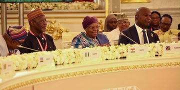 Delegates seated at a formal Russia–Africa conference table with microphones, floral garlands, and country nameplates.